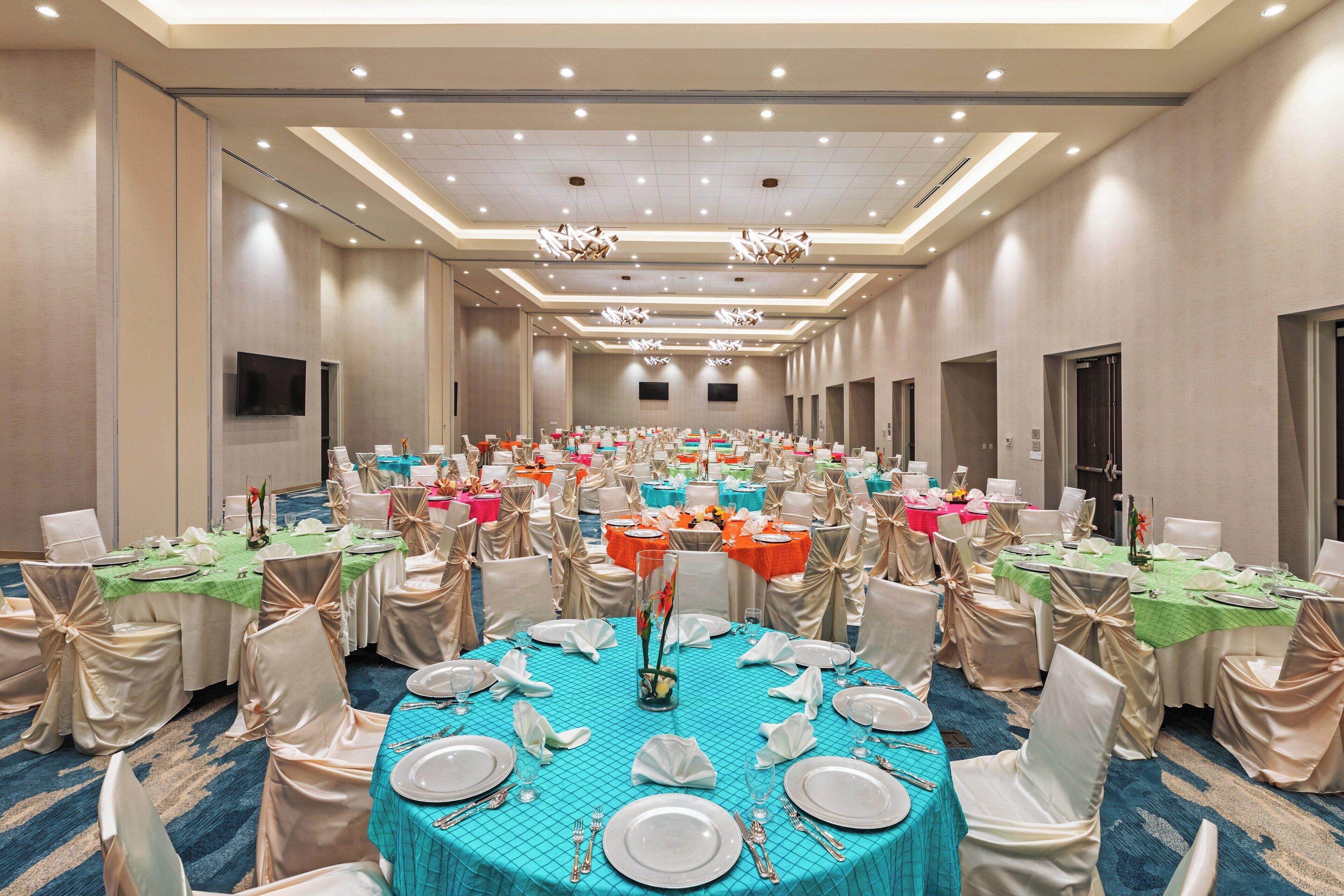A banquet hall with round tables, chairs, and a long corridor.