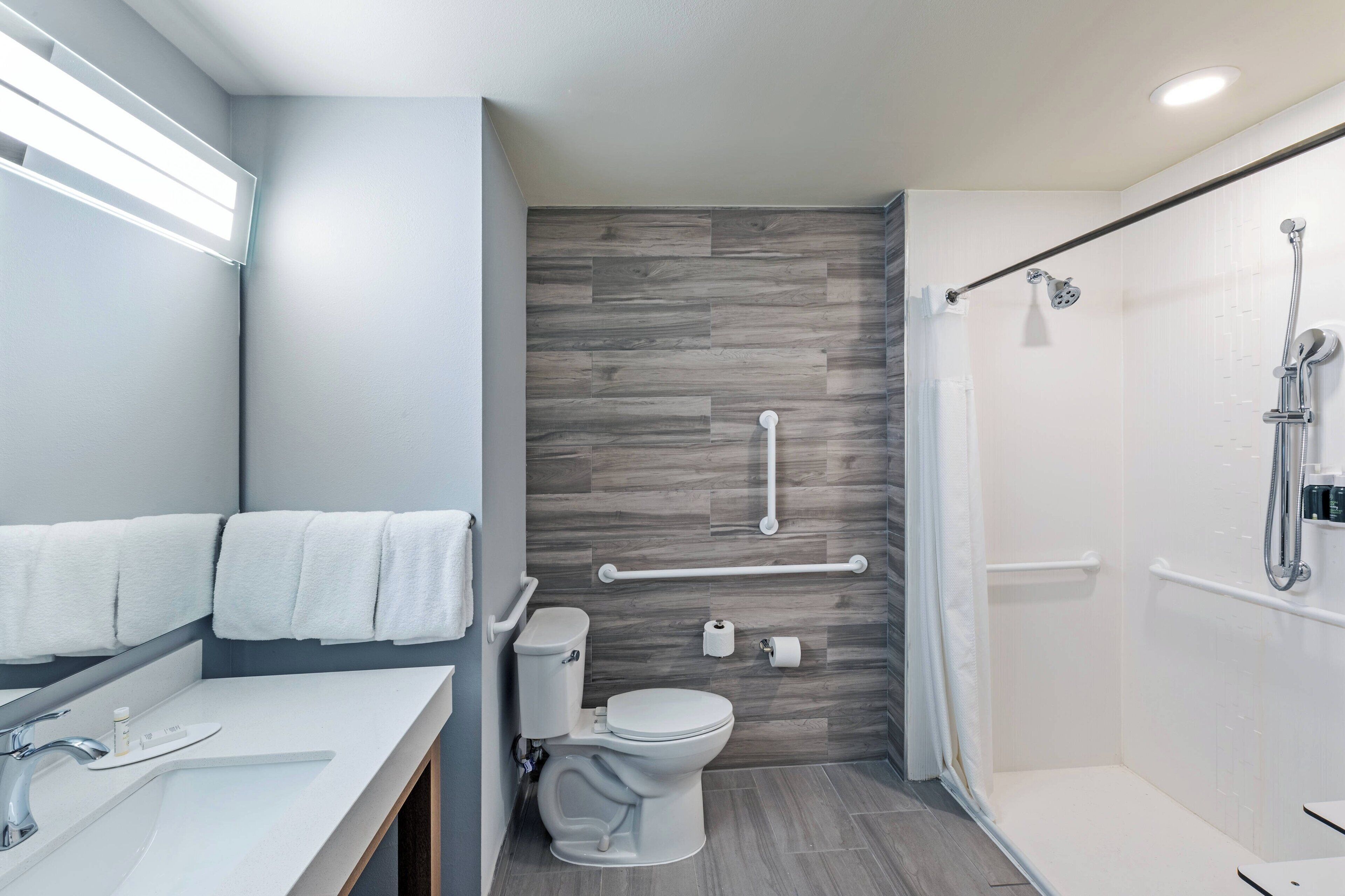 A modern bathroom with a shower, toilet, and sink.