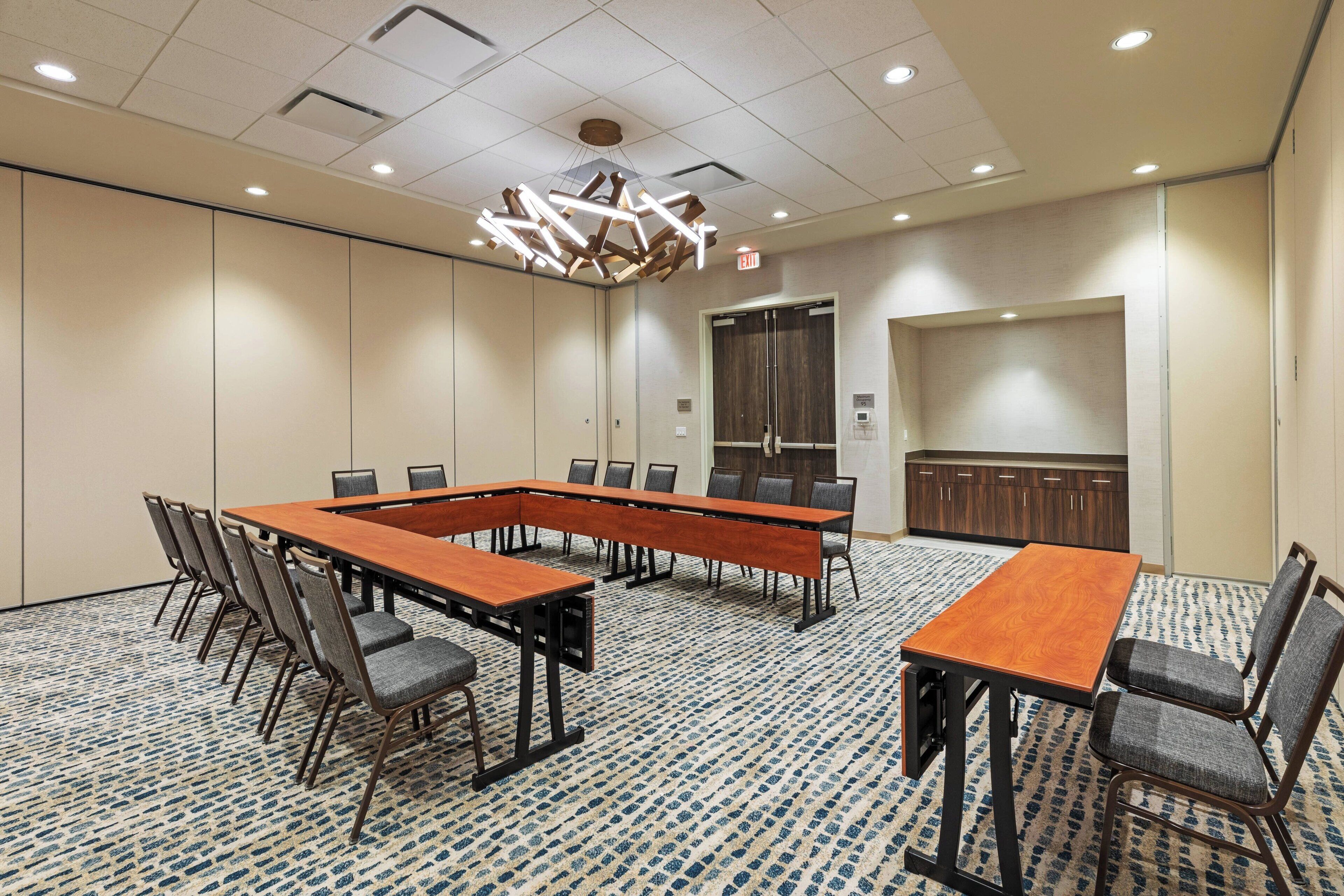 A conference room with a long table, chairs, a chandelier, and a patterned carpet.