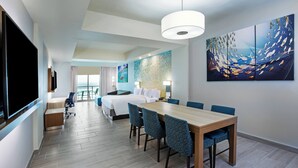A hotel room with a large bed, a dining table with chairs, a TV, and artwork on the walls. - Courtyard by Marriott South Padre Island (South Padre Island)
