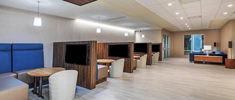 A modern hotel lobby with seating areas, wooden accents, and a large window.