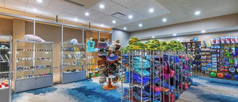 A well-lit retail space with shelves of sunglasses, hats, and folded clothing.