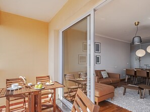 A modern living room with a sliding glass door leading to a balcony, a dining area with wooden furniture, and a seating area with a brown sofa and a coffee table. - Reis Magos III, for families with sea view. (Gaula)