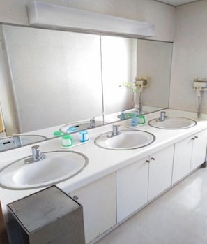 Bathroom features three sinks with faucets and mirrors above.