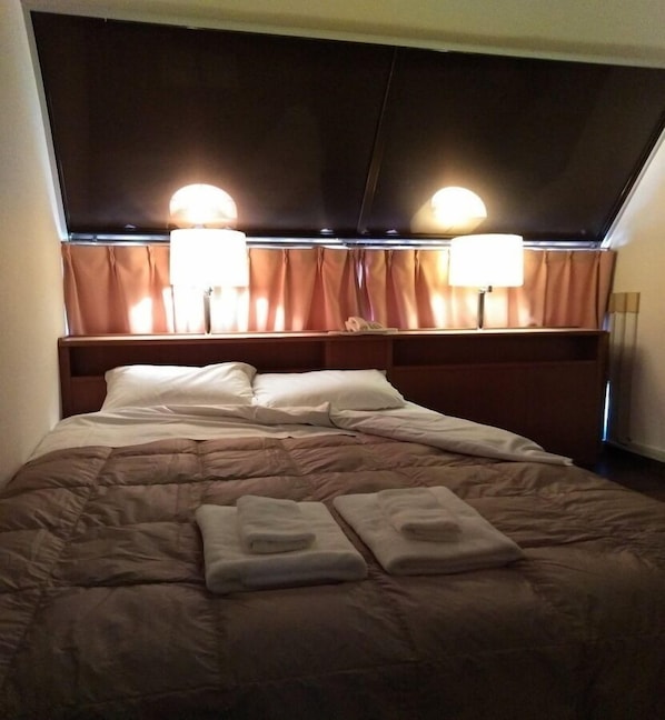 Relax in a cozy retreat with a neatly made bed, complete with a comfortable brown comforter and crisp white pillows.