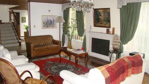 Una sala de estar con chimenea, un candelabro y una escalera que sube a otro nivel.