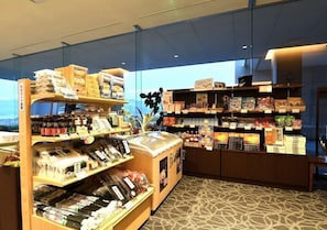 A bookstore with shelves of books and magazines, a display case with snacks, and a view through the glass wall.