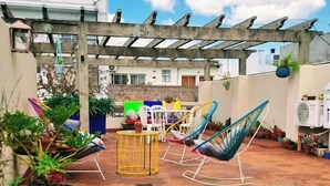 Uma área de pátio com pérgola, mobiliário externo e plantas em vasos.