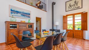 Un comedor con una mesa de vidrio, sillas negras, armarios de madera y un cuadro en la pared.