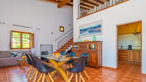 Un comedor con una mesa de vidrio, sillas negras y un mueble de madera.