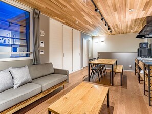 Un salon moderne avec un canapé, une table basse en bois et un coin repas comprenant une table et des chaises.