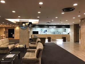 A reception area with a reception desk, seating area with sofas, and a counter with amenities.