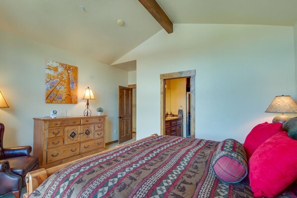 A bedroom with a bed, wooden dresser, and a painting on the wall. - Bear Crossing 845 Luxurious home mountain views private deck spacious floor plan (WINTER PARK)