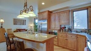 A kitchen with wooden cabinets, a large island with a sink, stainless steel appliances, and a window providing natural light.