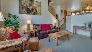 A spacious living room with a leather sofa, wooden coffee table, and a staircase leading to an upper level.