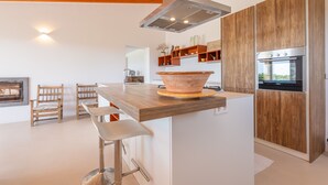 Een moderne keuken met een centraal eiland, houten kastjes en een inbouwoven.