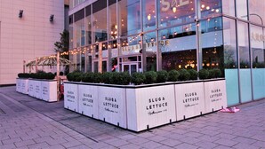 Een modern gebouw met grote ramen en een bord waarop staat 'SLUG & LETTUCE'.