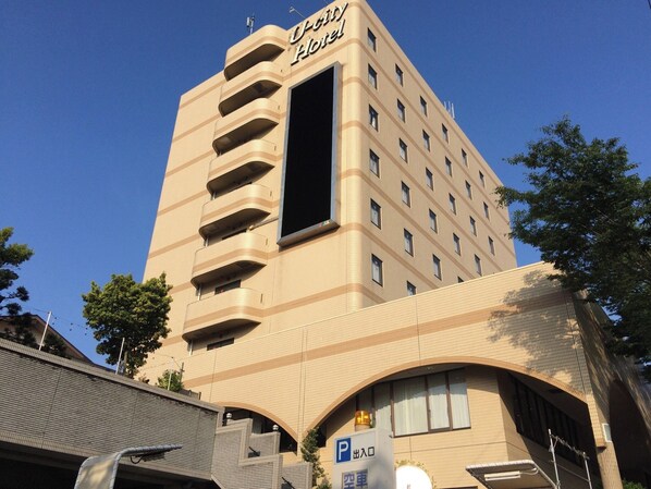 A hotel with a modern design, featuring a prominent 'U-city Hotel' sign, multiple balconies, and a parking sign indicating a parking area.