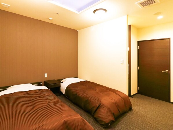 A hotel room with two single beds, a small bedside table, a nightstand, a door, and a ceiling light. - Nonsmoking Standard twin with toilet / Kanazawa Ishikawa (Kanazawa)