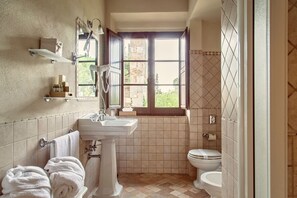 Un baño con lavamanos, inodoro y ventana con vista a follaje.