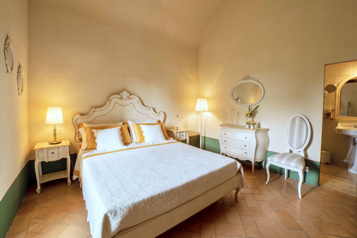 Une chambre à coucher avec un grand lit, une commode, une chaise et un miroir.