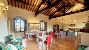 Un comedor amplio con sillas rojas y una mesa blanca, una cocina con una isla grande y una zona de estar acogedora con sofás verdes.