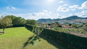 Eine Rasenfläche mit einer Hecke und Blick auf eine Stadt und Berge in der Ferne.