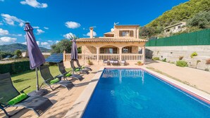 Eine Villa mit Swimmingpool, Sitzgelegenheiten im Freien und Blick auf die umliegende Landschaft.