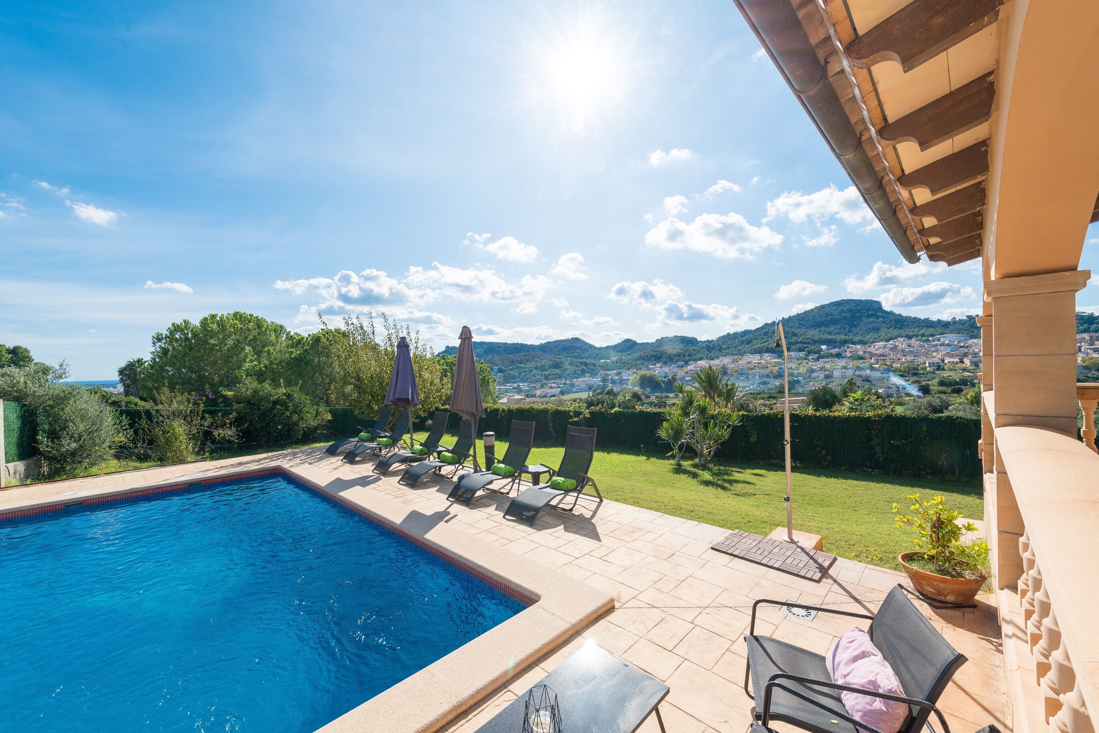 A swimming pool with lounge chairs and a view of a city and mountains in the background.