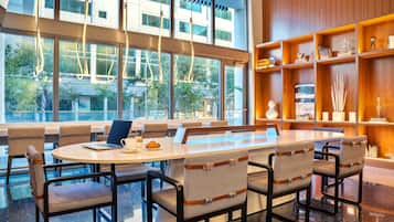 Une salle de conférence moderne, dotée d’une grande table, de chaises confortables et offrant une vue sur un bâtiment grâce à de larges fenêtres.
