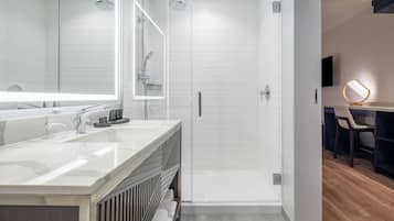A modern bathroom with a large mirror, a shower, and a vanity with a sink.