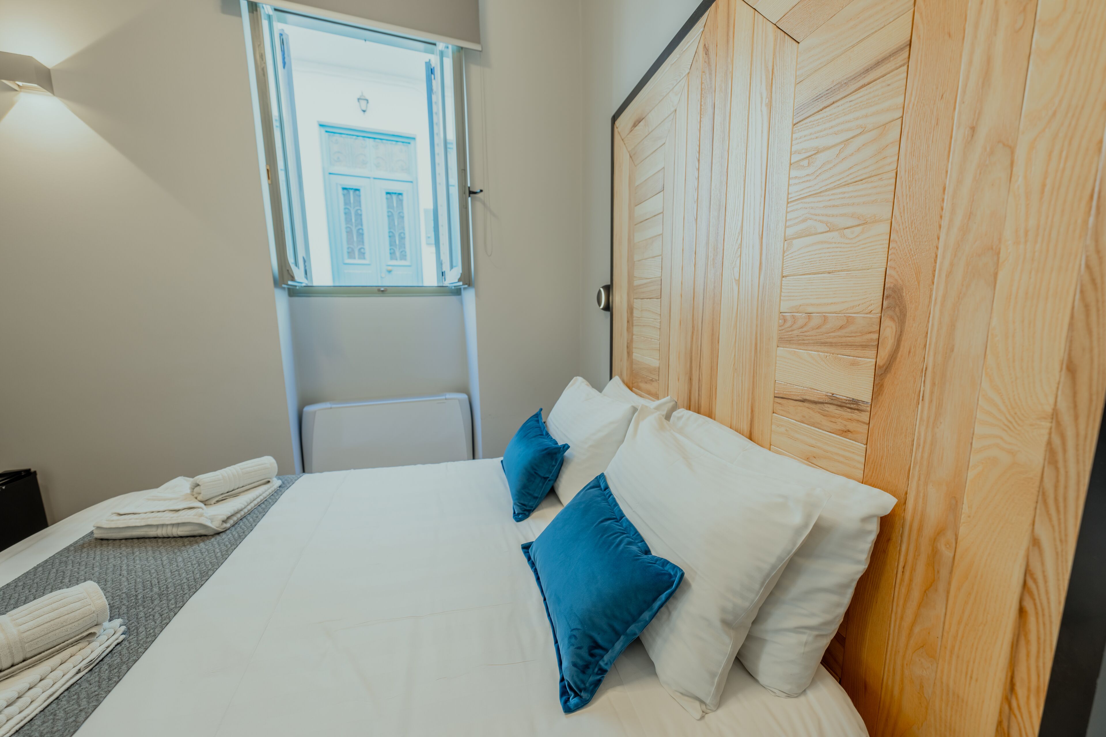 Una habitación de hotel con una cama grande, un cabecero de madera, una ventana y un radiador.