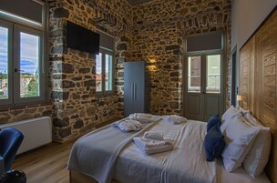 Un dormitorio con paredes de piedra, una cama con toallas, un armario y un televisor fijado a la pared.