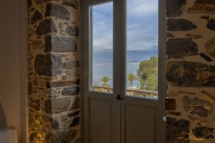 Un muro de piedra con una puerta que da a un balcón con vistas al mar y palmeras.