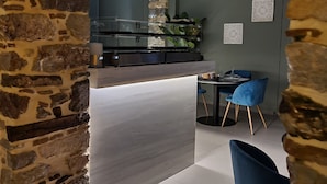 Een moderne keuken met een stenen boog, een eethoek met blauwe stoelen en een hangplant.