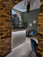Una cocina moderna con un arco de piedra, un comedor con sillas azules y una planta colgante.