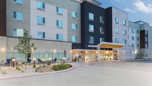 A multi-story hotel with a modern design, featuring a prominent entrance with outdoor seating and a covered area.