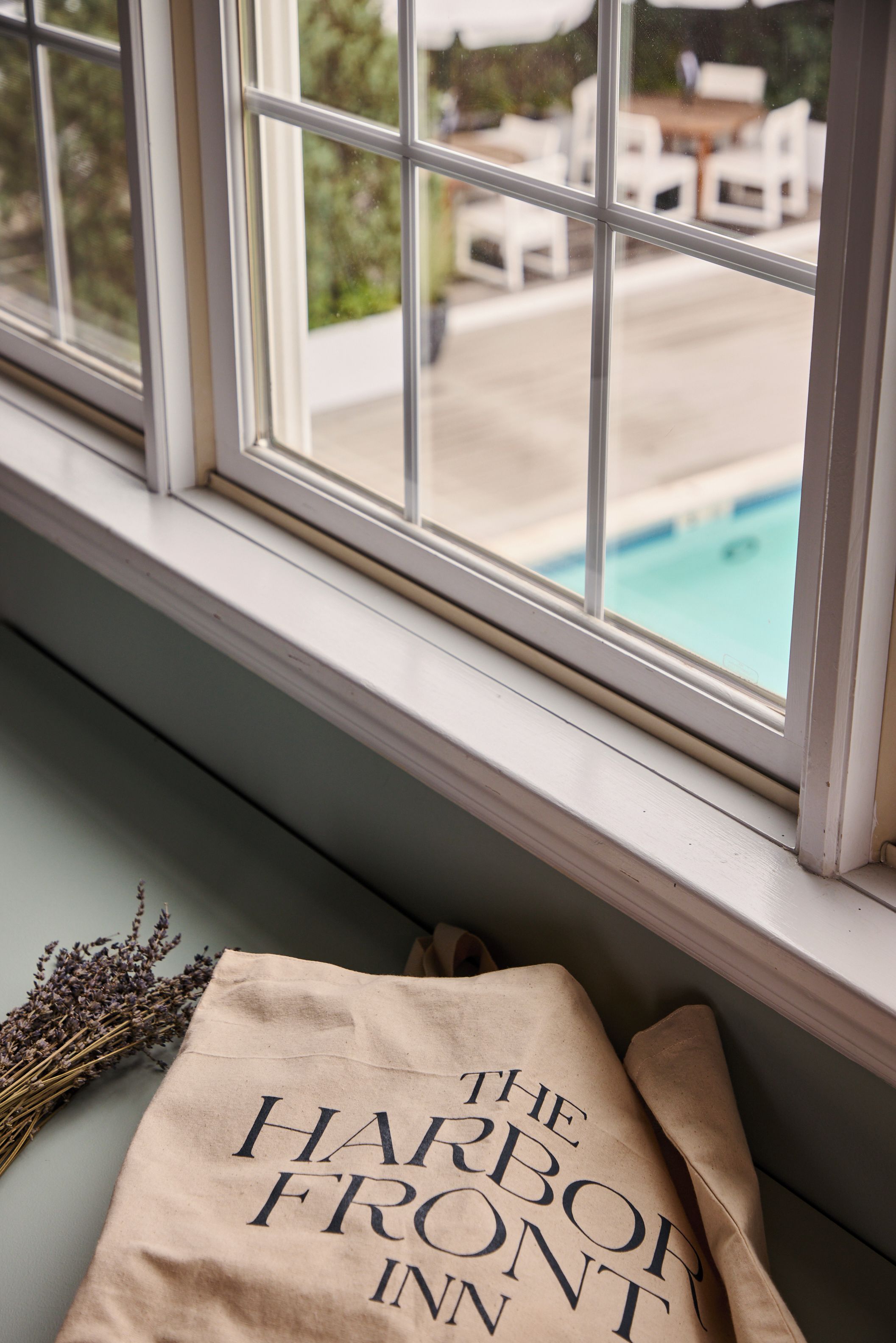 A window with a view of a swimming pool and outdoor furniture.