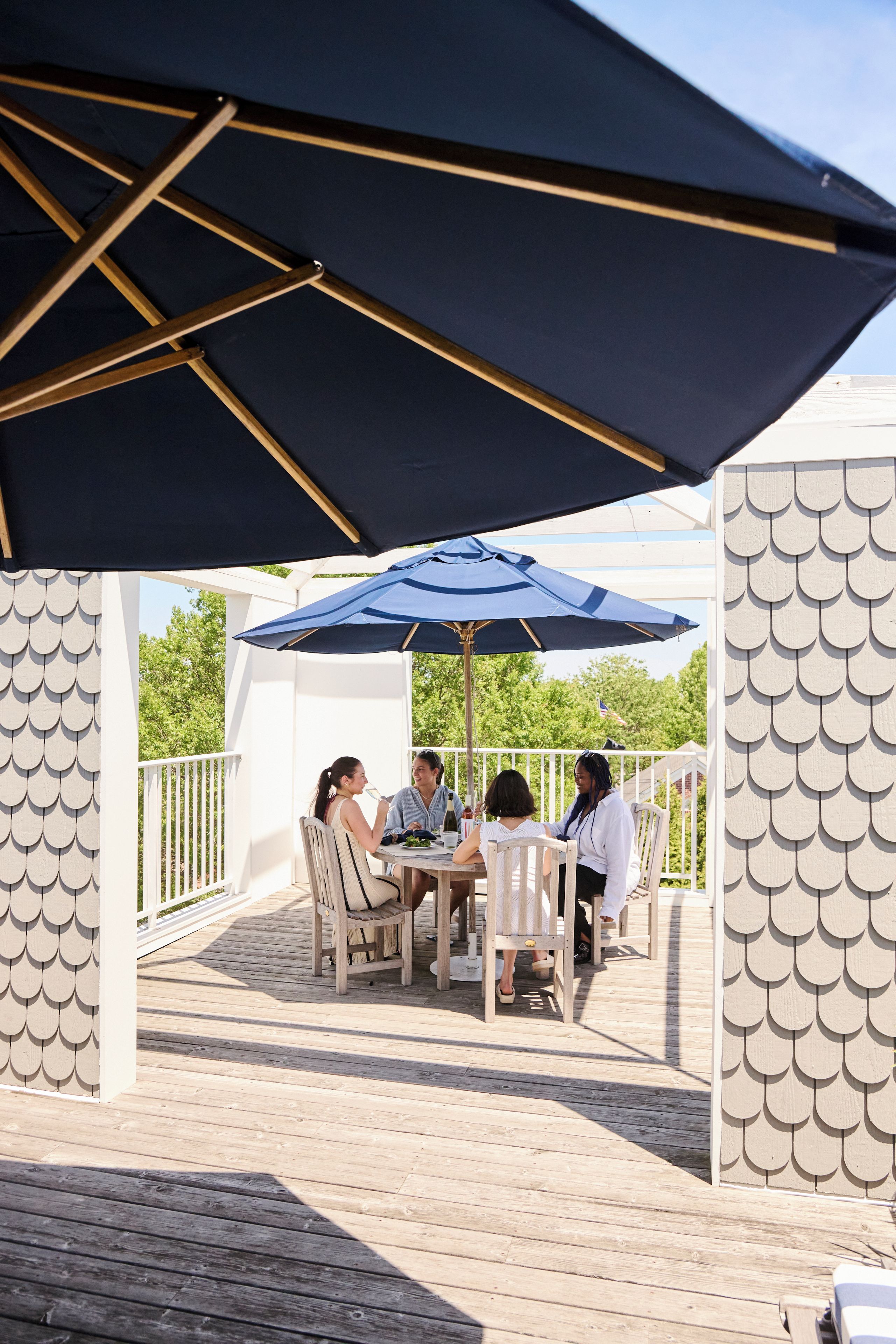 An outdoor patio with a table and chairs under a large umbrella.