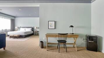 Una camera d'albergo con un letto, una scrivania, una sedia e un piccolo frigorifero.