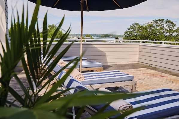 Una terraza en la azotea con sillones de descanso, una mesa de madera y vistas al paisaje.