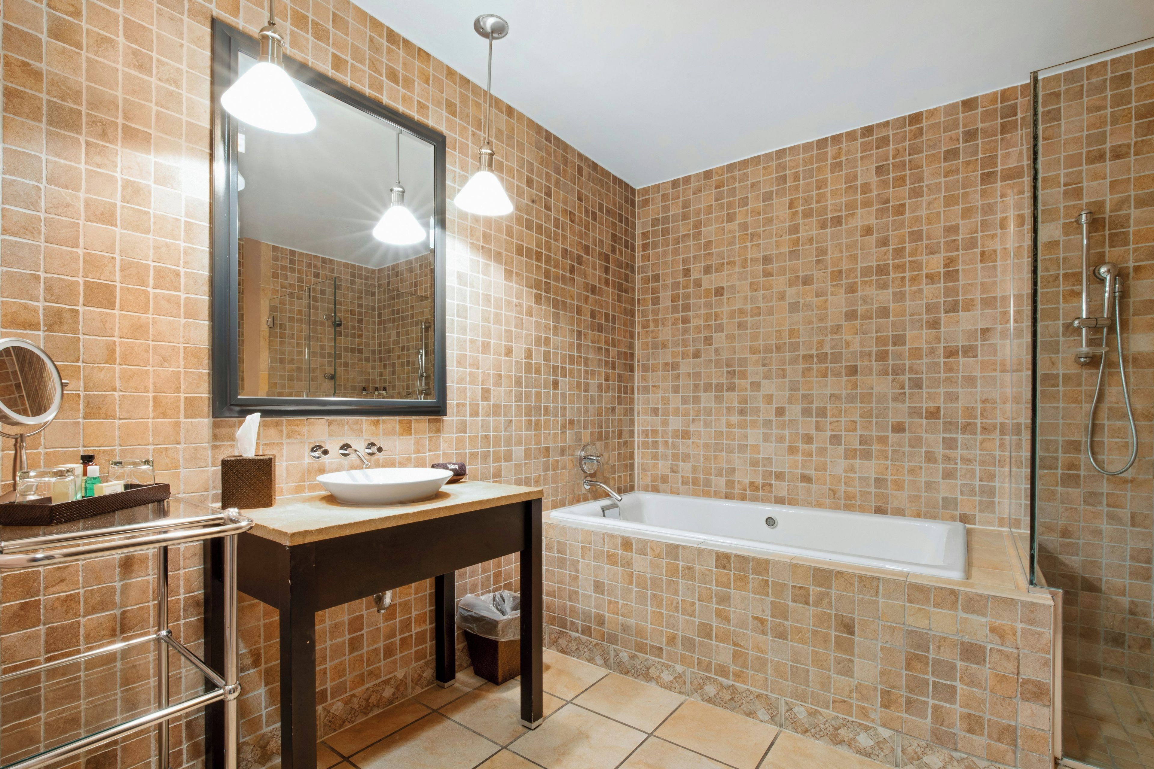 A bathroom with a sink, mirror, vanity, and a shower area.