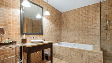 A bathroom with a sink, mirror, vanity, and a shower area.