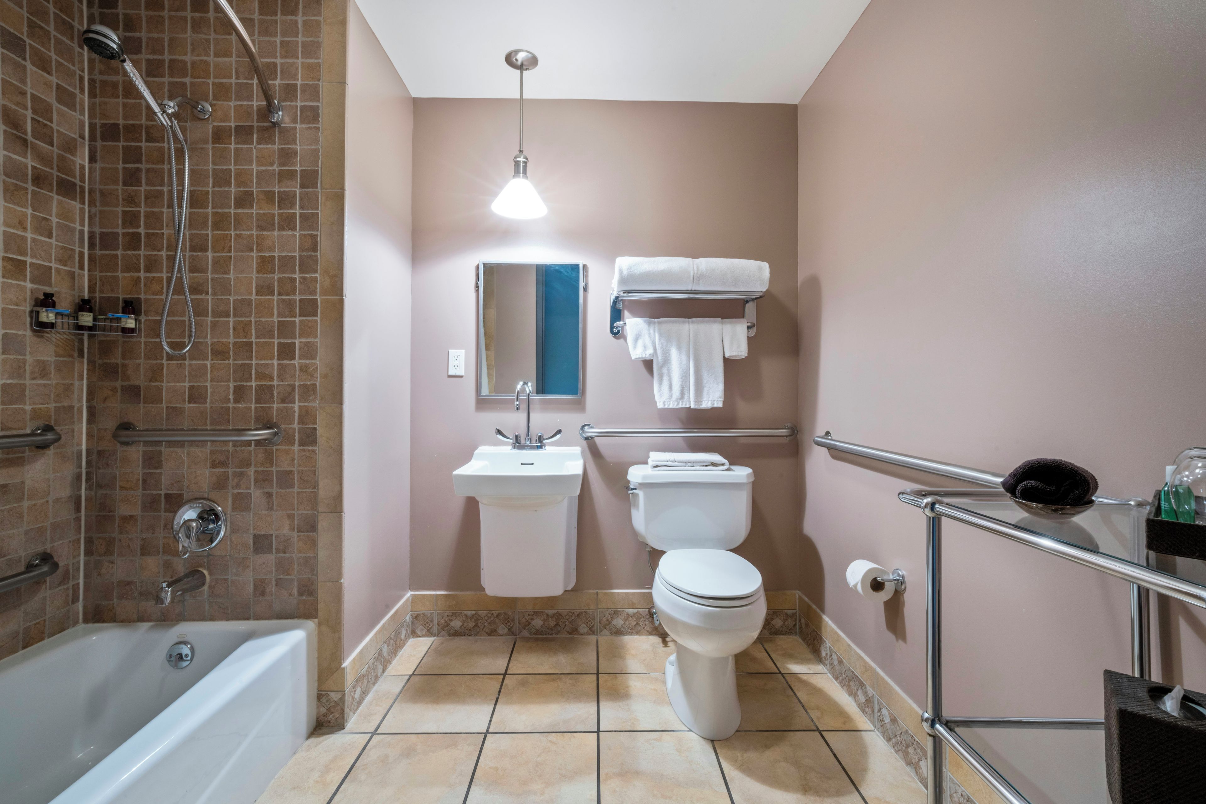 A bathroom with a shower, sink, toilet, and a glass shelf with toiletries.
