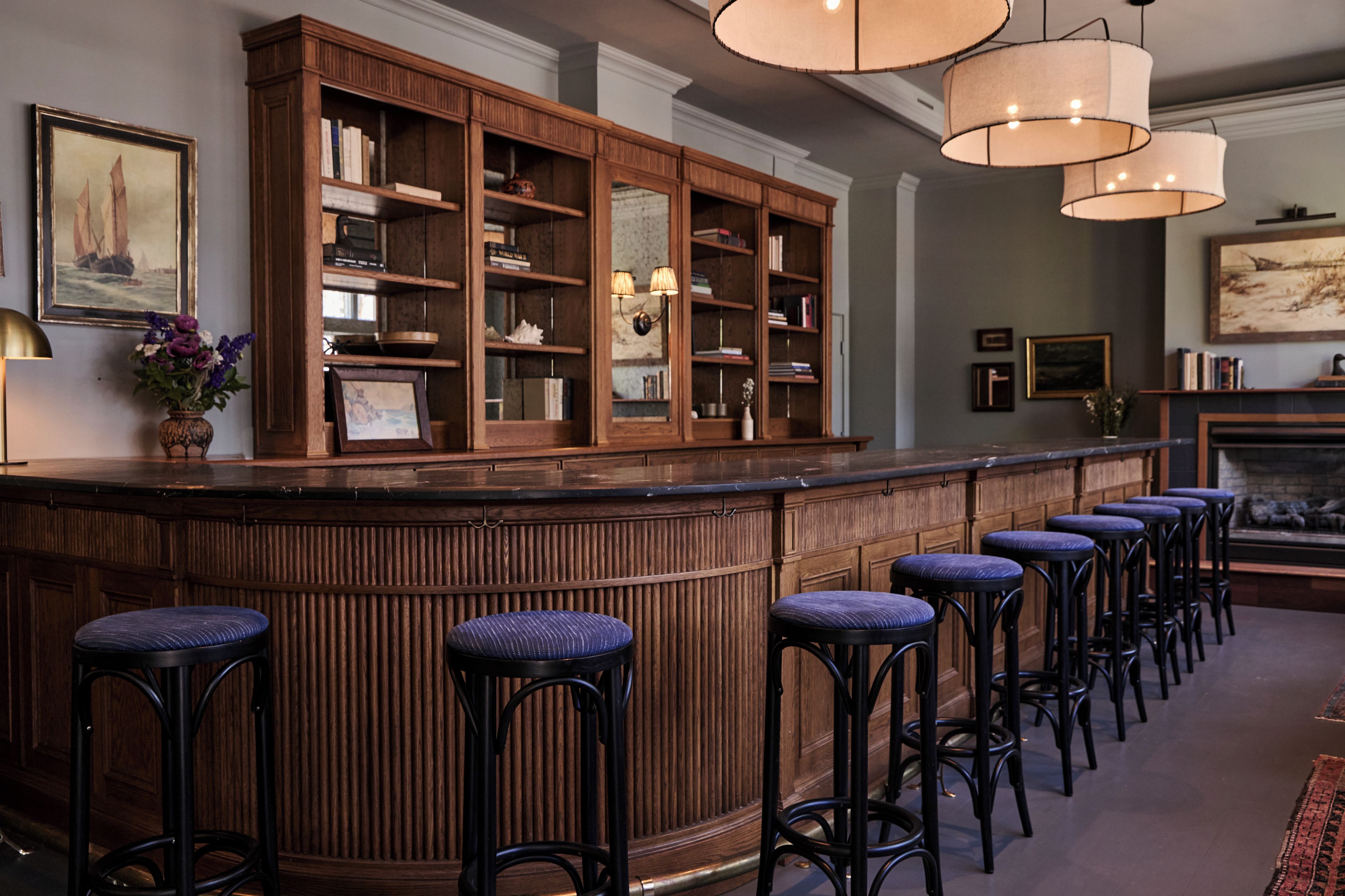 A bar area with wooden bar stools and a bookshelf.