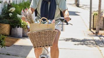 Une personne fait du vélo sur un trottoir, et son vélo est équipé d'un panier à l'avant.