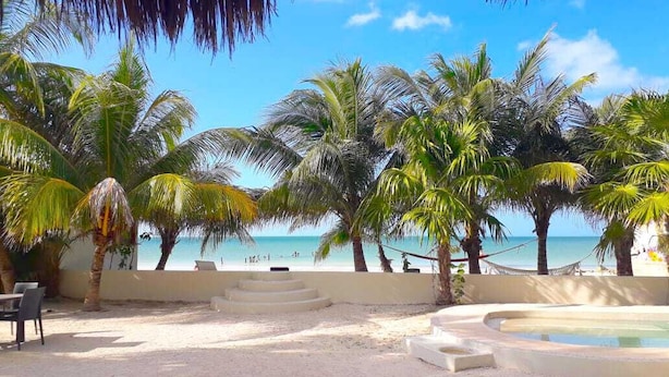 A beachside resort with palm trees, a pool, and a view of the ocean. - Hotel Boutique La Puerta Azul Beachfront - Adults Only (Isla Holbox)