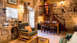 A cozy stone-walled room with a dining area, wooden furniture, and a staircase. - Charming Retreat: experience rustic elegance in this beautifully converted fh. (Santa Lucija)