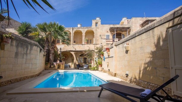 A pool area with a lounge chair, a stone building with arches, and potted plants. - Charming Retreat: experience rustic elegance in this beautifully converted fh. (Santa Lucija)