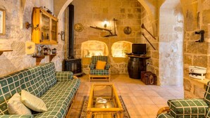 A cozy stone-walled room with a fireplace, a sofa, a small table, and a television. - Charming Retreat: experience rustic elegance in this beautifully converted fh. (Santa Lucija)
